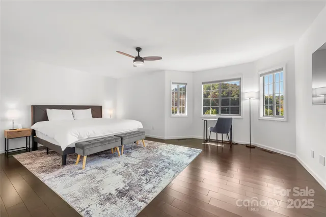 a spacious bedroom with a bed and wooden floor