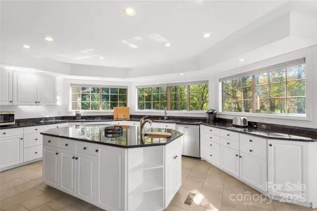 a kitchen with granite countertop a stove a sink a refrigerator and white cabinets with wooden floor
