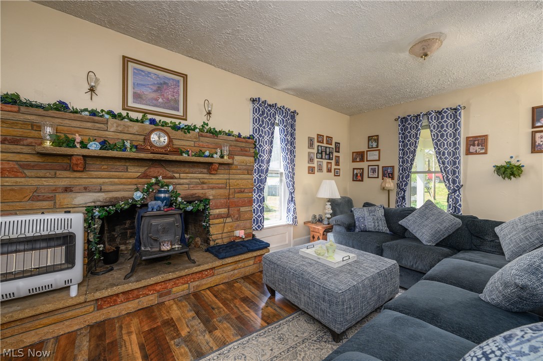 79405 Freeport Tippecanoe Road Tippecanoe, OH 44699 - Photo 27 of 42 Living room featuring a wood stove, dark wood-type flooring, and a textured ceiling