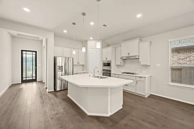 a large kitchen with stainless steel appliances a sink a refrigerator and a stove top oven