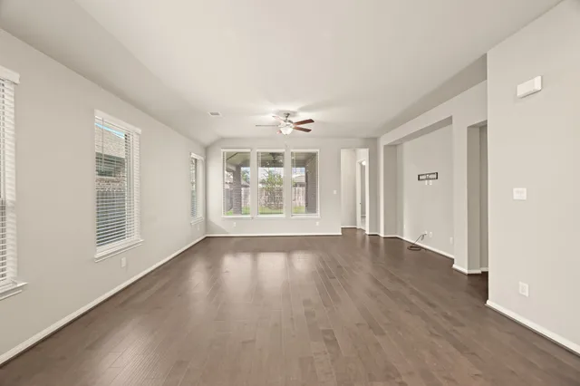 an empty room with wooden floor and windows