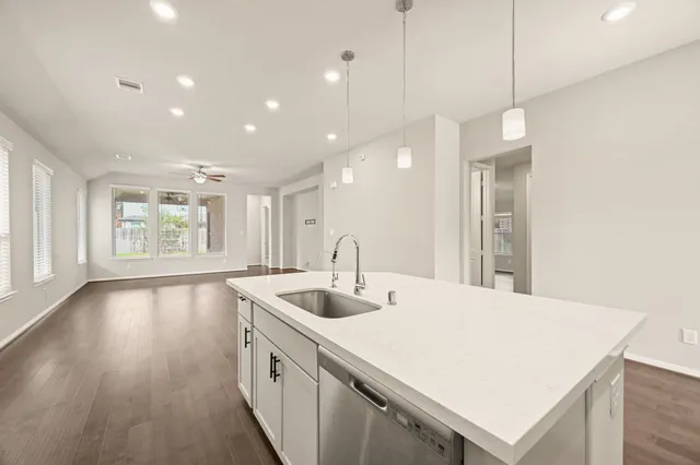 a kitchen with stainless steel appliances granite countertop a sink a oven a wooden cabinets and wooden floors