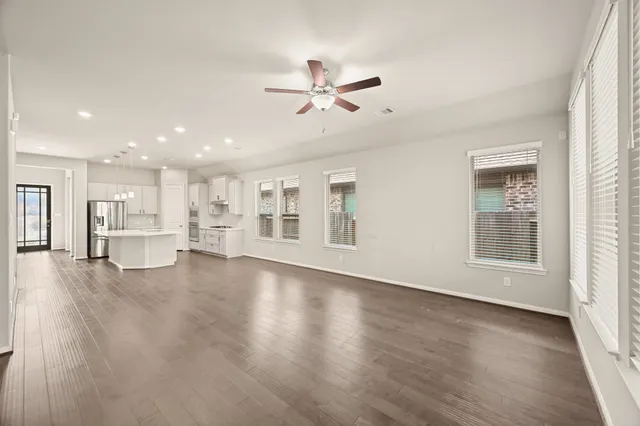 a view of an empty room with a window and wooden floor