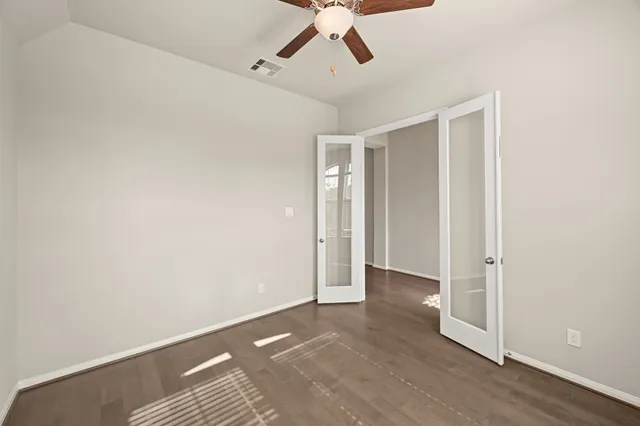 an empty room with a ceiling fan and wooden floor