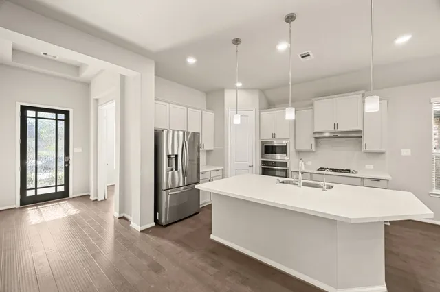 a large kitchen with stainless steel appliances kitchen island a stove a refrigerator a center island a stove and a refrigerator with wooden floor