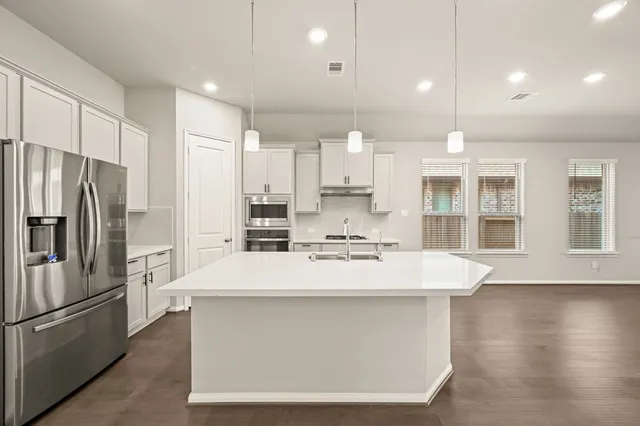 a kitchen with kitchen island a stove a refrigerator and a sink with wooden floor