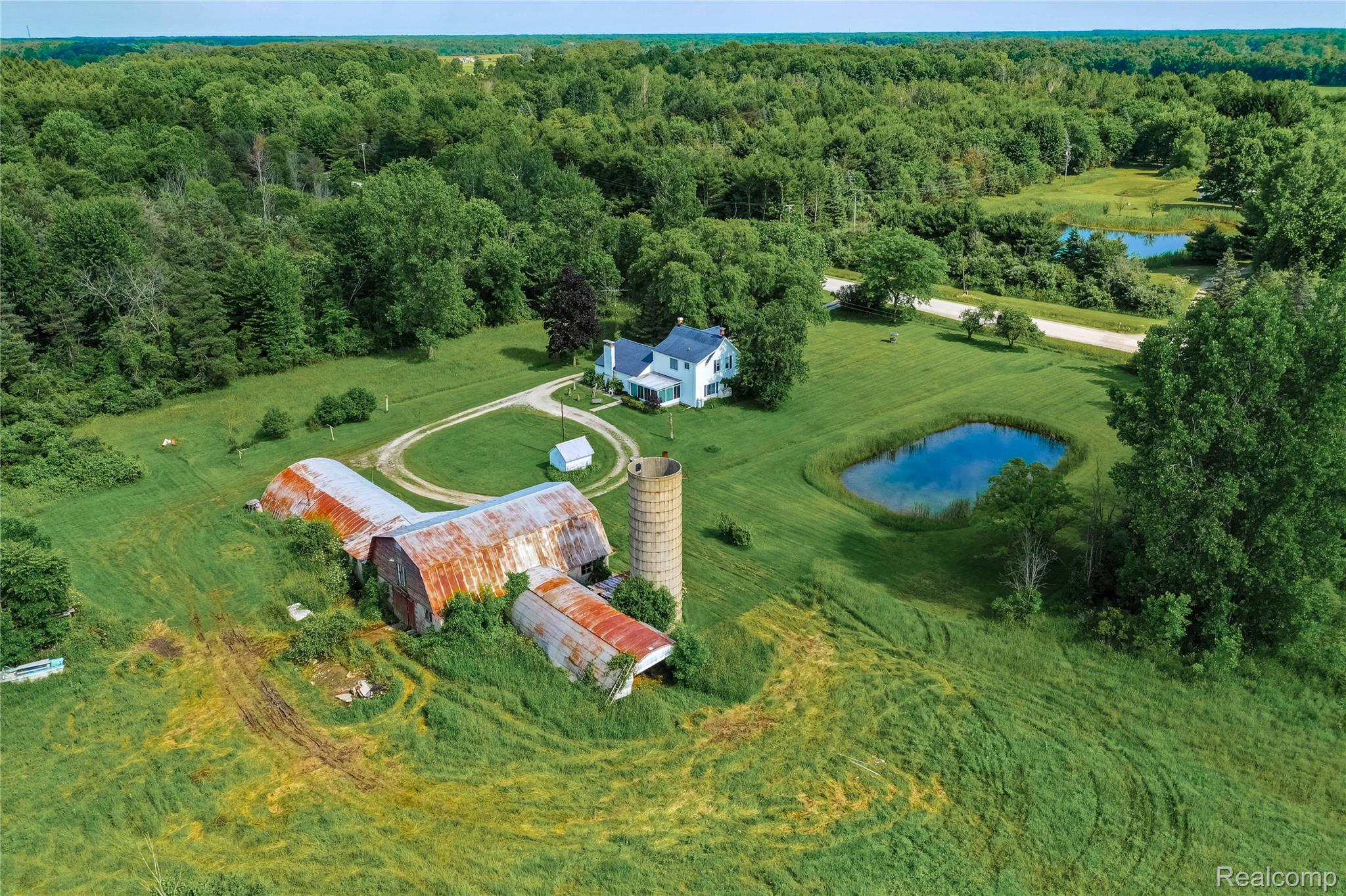8384 Imlay City Road Avoca, MI 48006 - Photo 2 of 39 Expansive rural property featuring a white residence, multiple outbuildings, a silo, and a pond
