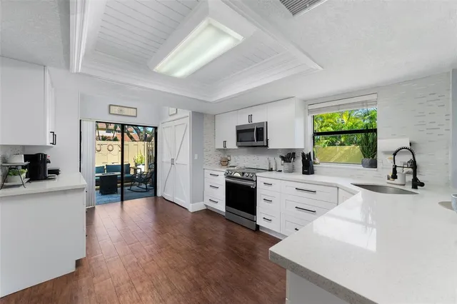 a kitchen with stainless steel appliances white cabinets a sink dishwasher a stove and a refrigerator with wooden floor