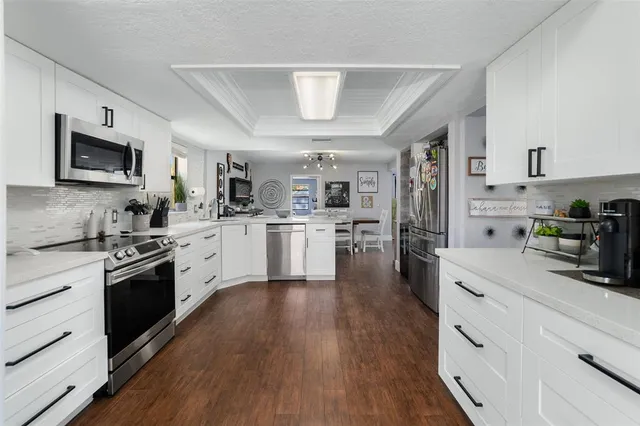 a kitchen with stainless steel appliances granite countertop a stove top oven a sink dishwasher and a refrigerator with wooden floor