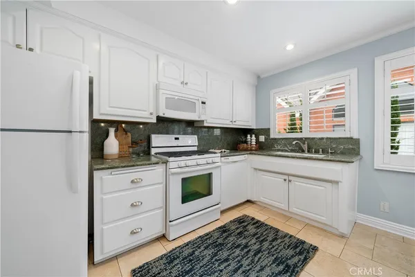 a kitchen with granite countertop white cabinets and white appliances
