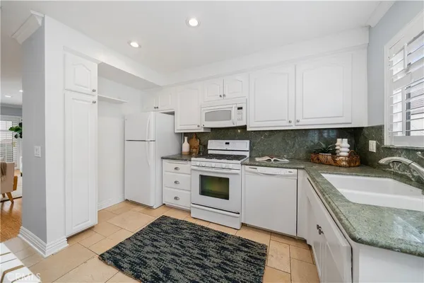 a kitchen with granite countertop a sink stove and refrigerator