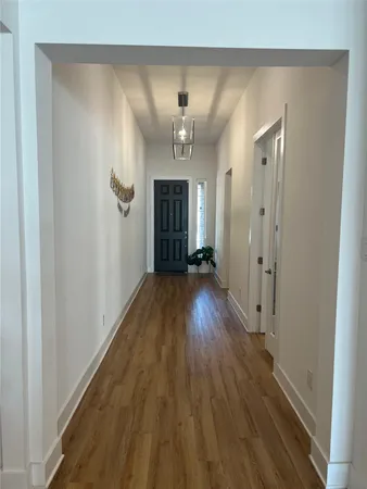 a view of a hallway with wooden floor and a chandelier