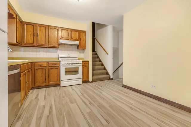 a view of a kitchen with wooden floor electronic appliances and stairs