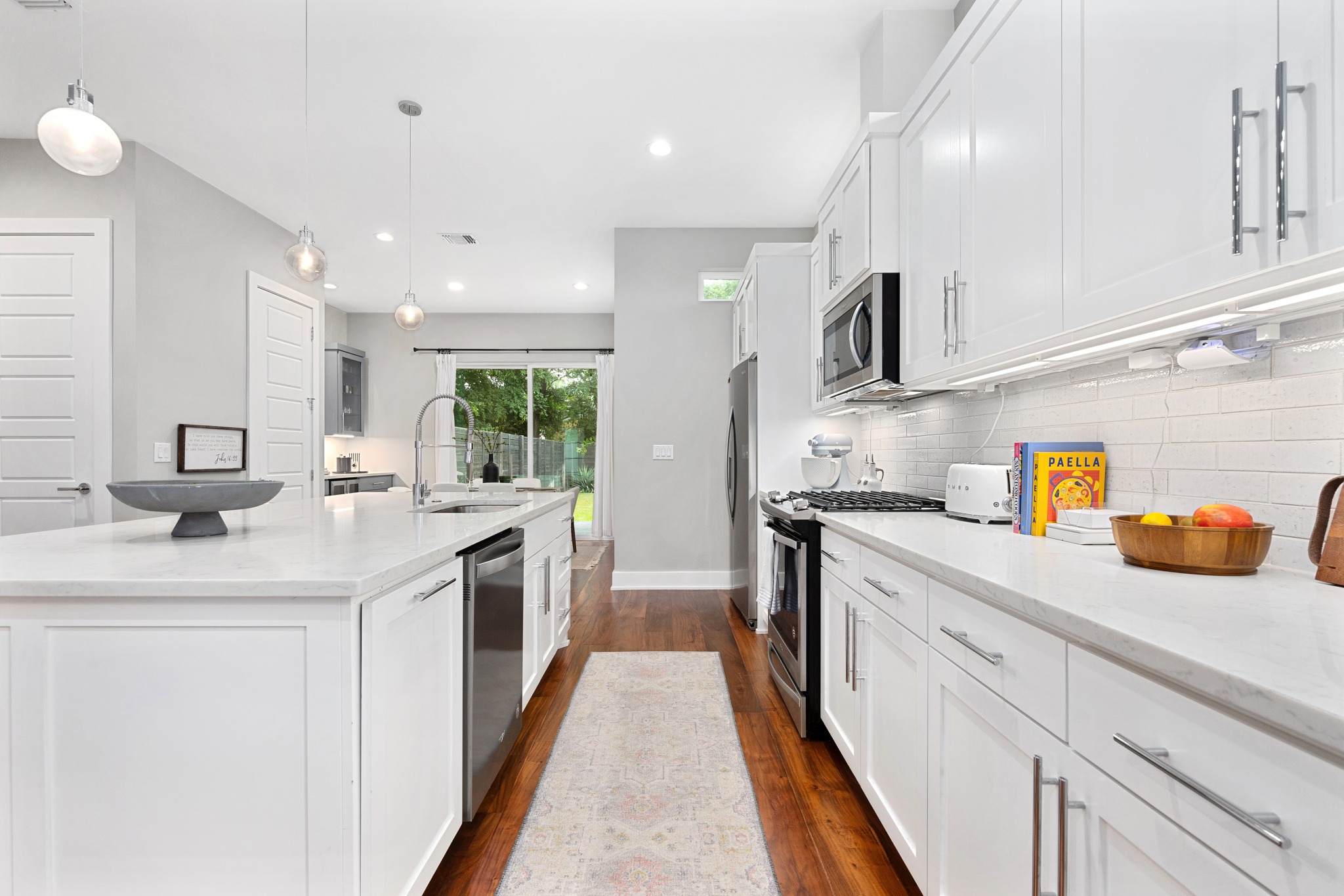 1103 Saucedo Street, Unit 1 Austin, TX 78721 - Photo 12 of 40 Bright white cabinetry and a large center island define this inviting, naturally lit culinary space.