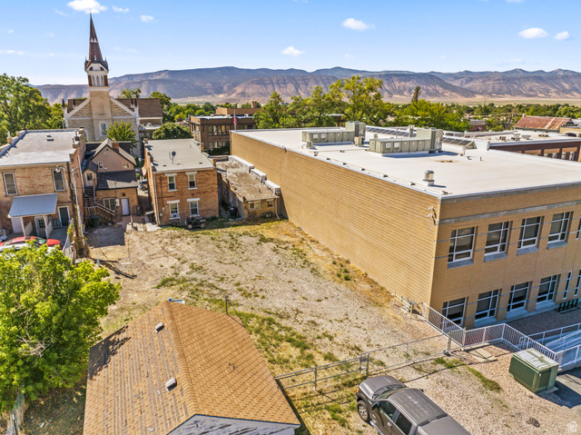 69 South Main Street Manti, UT 84642 - Photo 11 of 44 Expansive undeveloped lot with surrounding structures, featuring an adjacent brick building with multiple windows and a flat roof