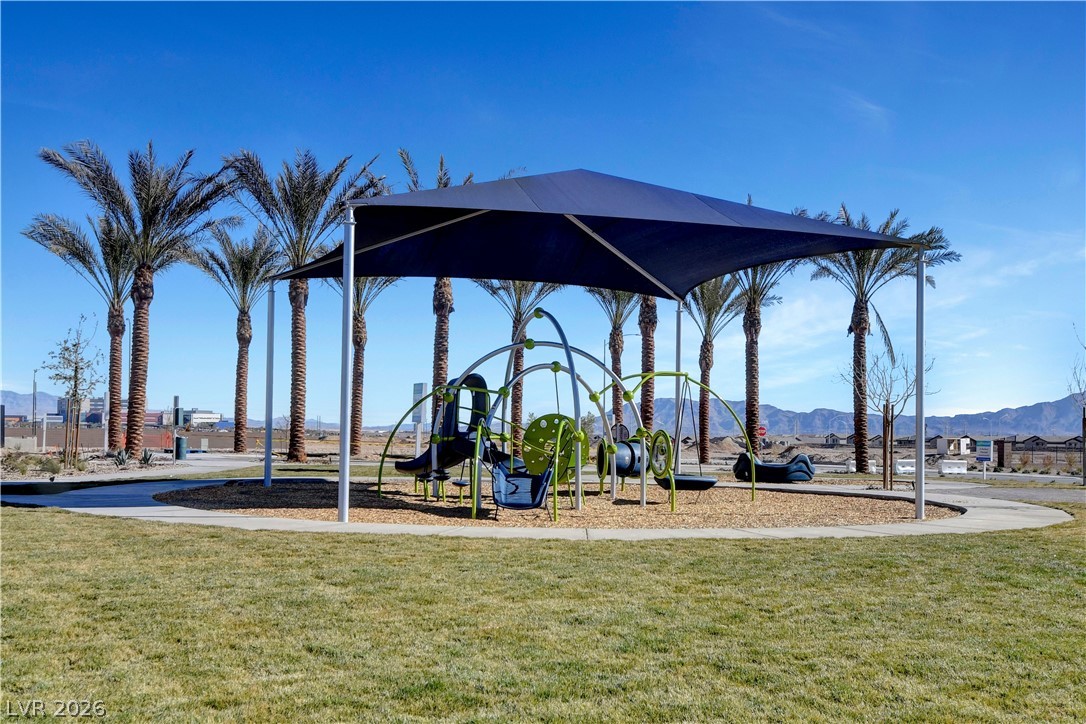 6924 Spicy Merlot Street North Las Vegas, NV 89086 - Photo 48 of 83 A community park with a shaded play structure surrounded by palm trees and mountain views.