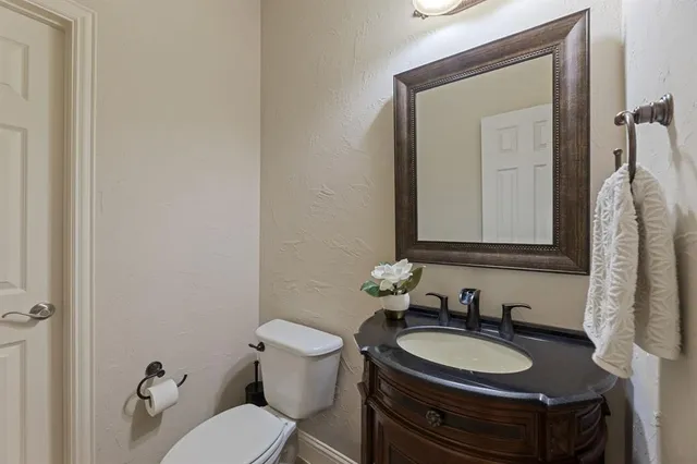 a bathroom with a granite countertop toilet sink mirror and vanity