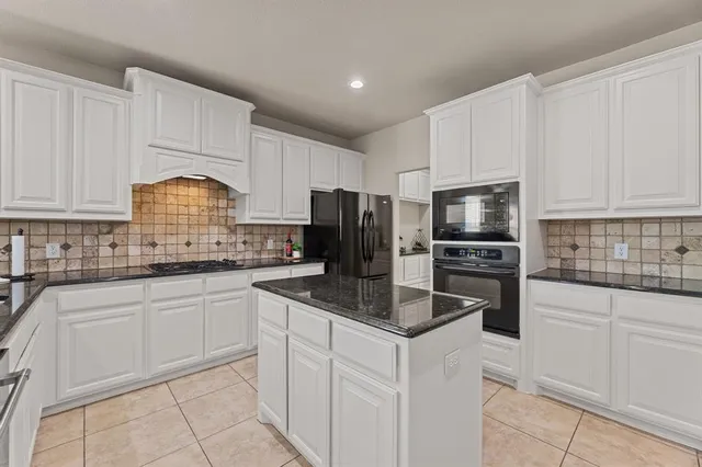 a kitchen with granite countertop white cabinets and stainless steel appliances