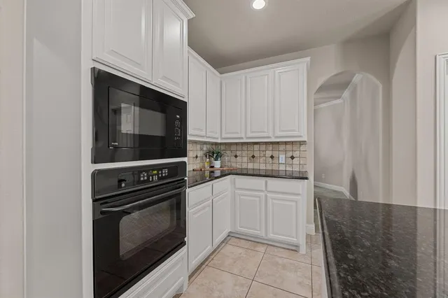 a kitchen with granite countertop white cabinets and stainless steel appliances