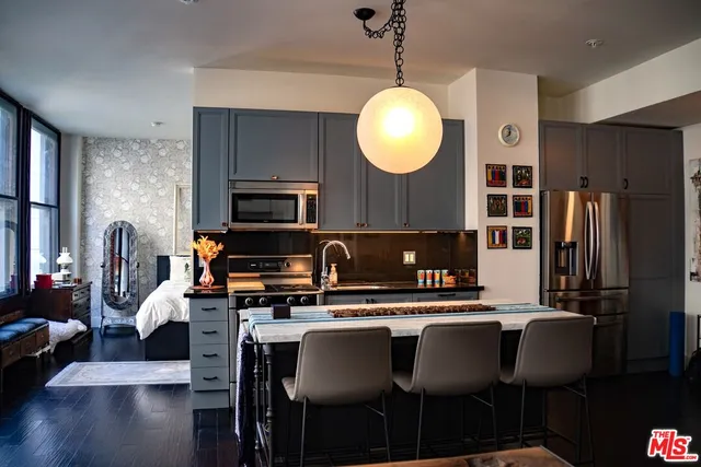 a kitchen with stainless steel appliances granite countertop a stove a refrigerator a kitchen island a dining table and chairs