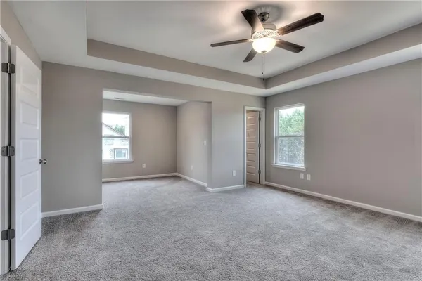 a view of an empty room and a ceiling fan and window