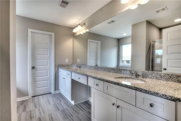 a bathroom with a granite countertop double vanity sink and mirror