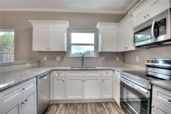 a kitchen with white cabinets appliances a sink and a window