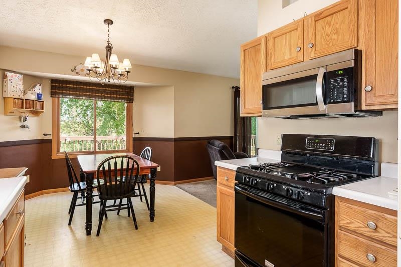 5406 Torque Road Loves Park, IL 61111 - Photo 22 of 40 a kitchen with stainless steel appliances a stove a microwave a dining table and chairs