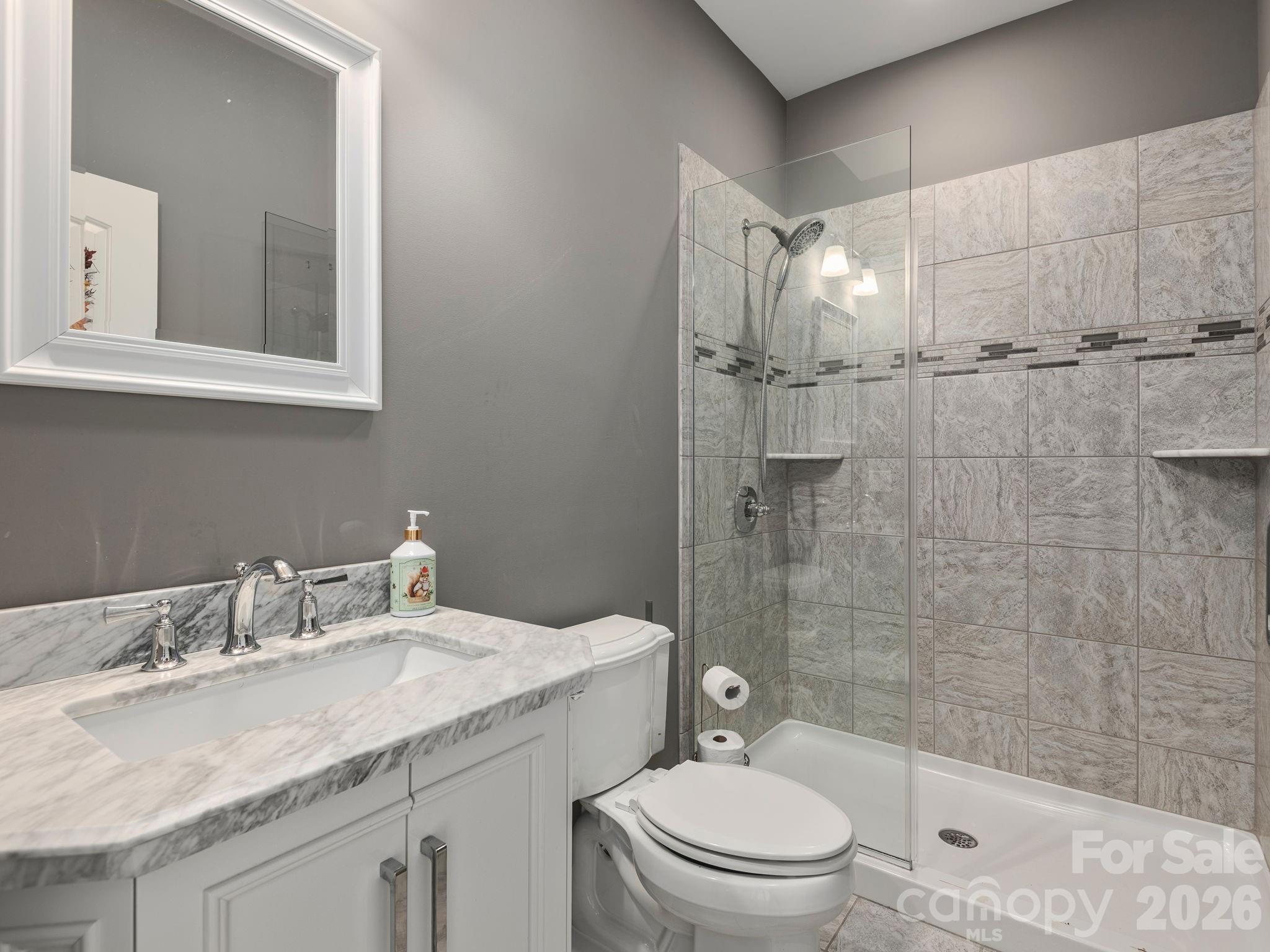 193 Youngs Cove Road Candler, NC 28715 - Photo 24 of 48 a bathroom with a granite countertop sink a toilet and shower