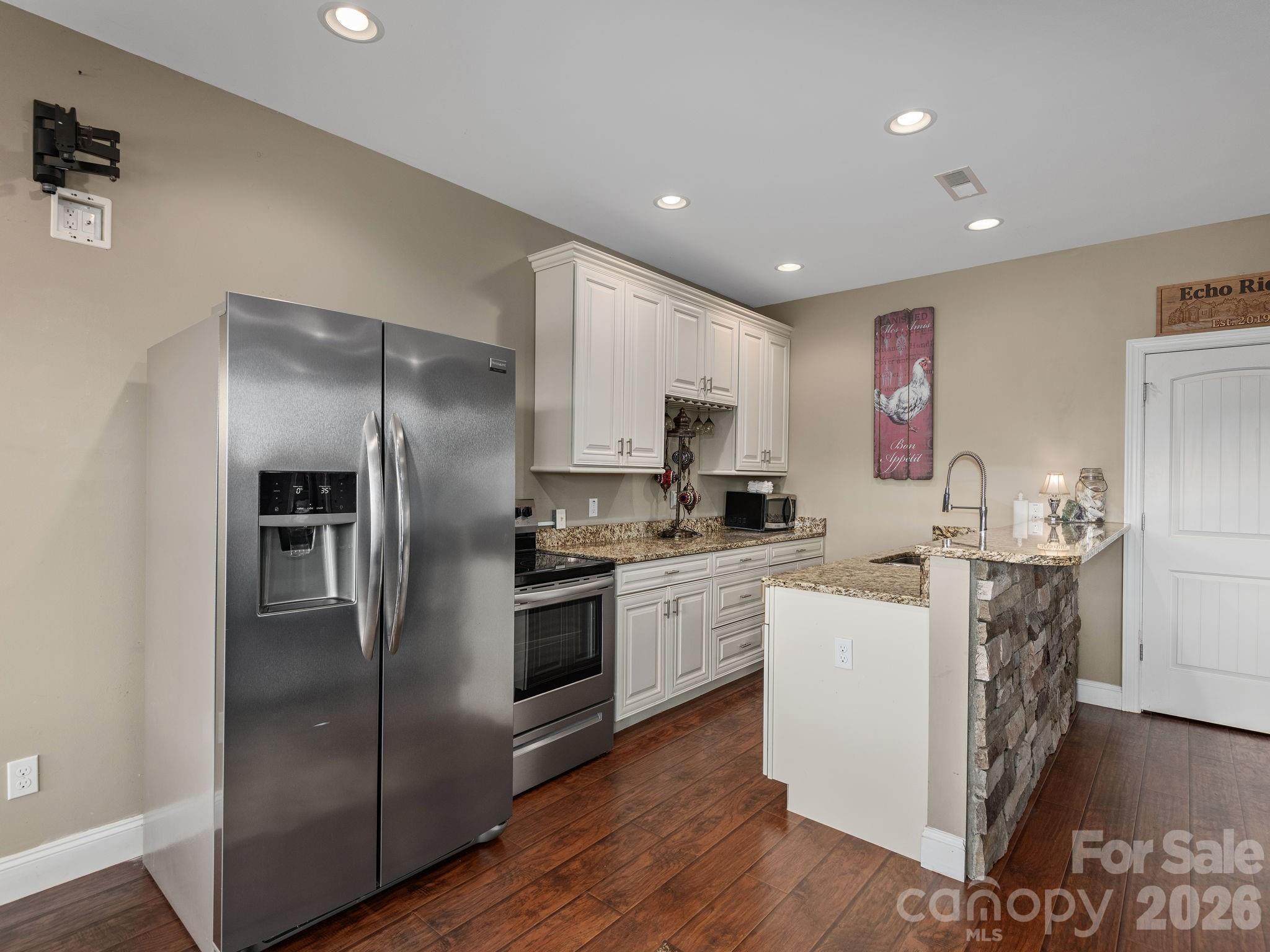 193 Youngs Cove Road Candler, NC 28715 - Photo 27 of 48 a kitchen with stainless steel appliances granite countertop a refrigerator a stove top oven a sink and dishwasher with wooden floor