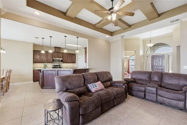 a living room with furniture kitchen view and a chandelier