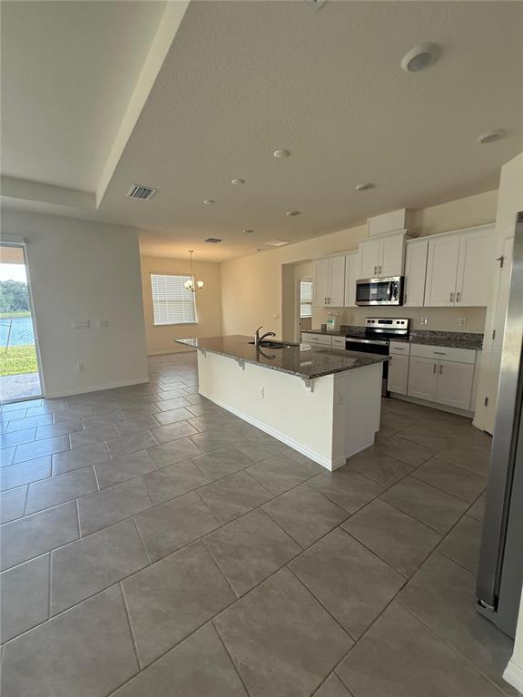 1729 Bull Hill Road Kissimmee, FL 34744 - Photo 3 of 34 a large kitchen with granite countertop a stove a sink a microwave and a refrigerator