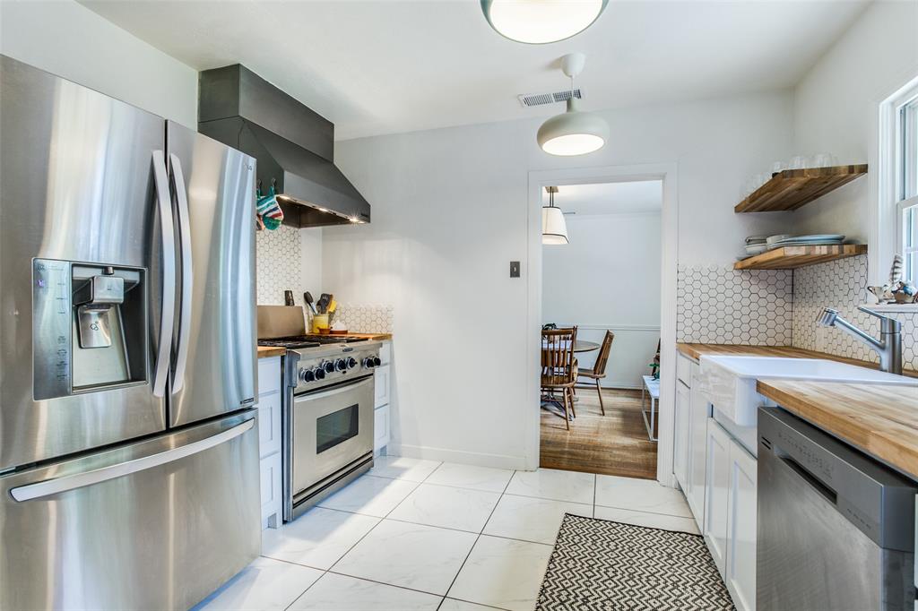 8619 Angora Street Dallas, TX 75218 - Photo 12 of 24 Kitchen with wall chimney exhaust hood, light hardwood / wood-style floors, tasteful backsplash, stainless steel appliances, and butcher block counters