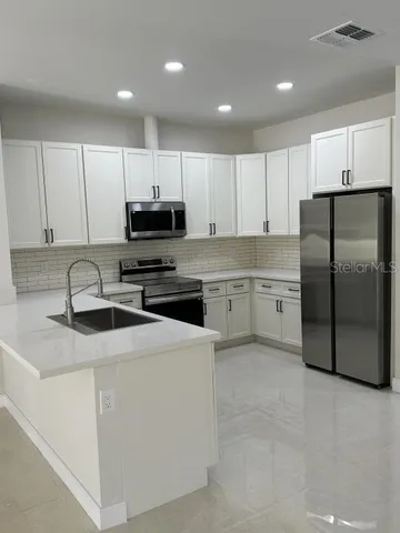 a kitchen with stainless steel appliances granite countertop a refrigerator stove a sink and a microwave