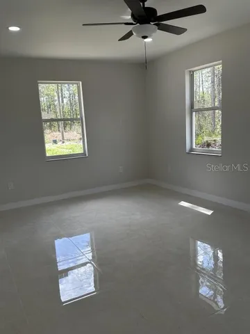 en empty room with windows and ceiling fan