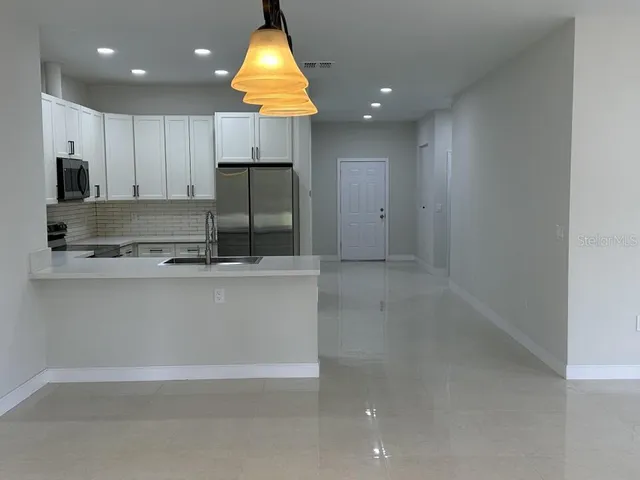 a kitchen with kitchen island white cabinets appliances and a sink