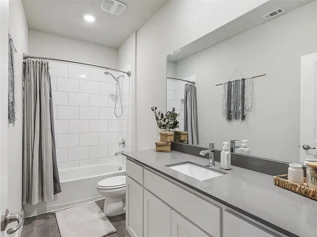 a bathroom with a granite countertop sink a toilet a mirror and shower