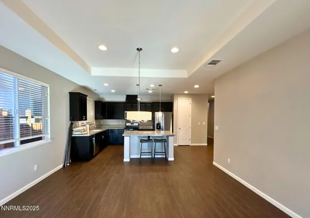 a view of kitchen with kitchen island microwave stove refrigerator and wooden floor