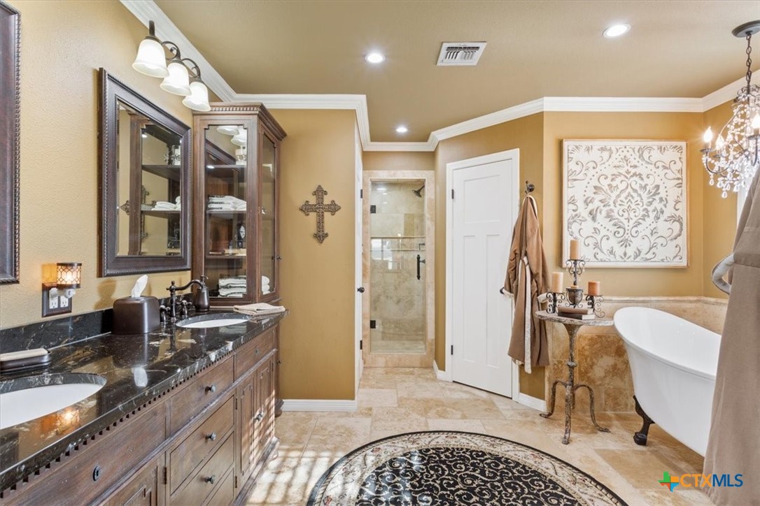 6409 3 Forks Road Belton, TX 76513 - Photo 28 of 40 a spacious bathroom with a double vanity sink a mirror a bathtub and next to a window