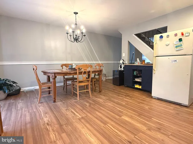 a dining room with wooden floor a chandelier a wooden table and chairs