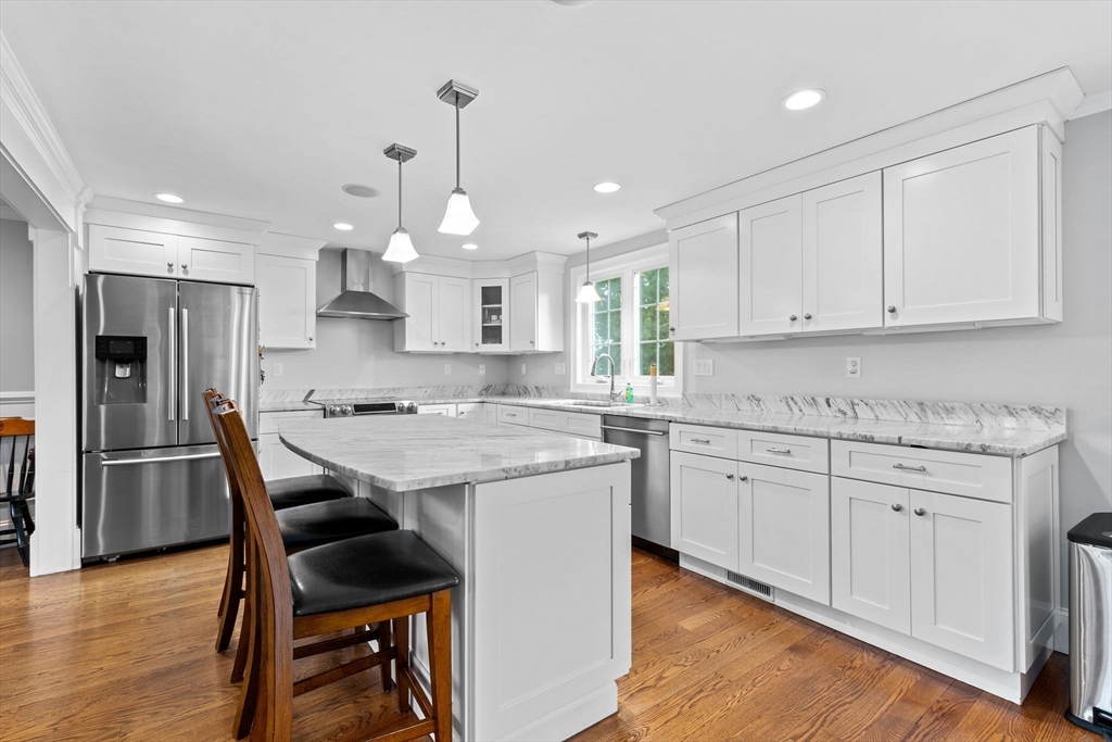 48 Atwill Road Boston, MA 02132 - Photo 7 of 36 a kitchen with stainless steel appliances granite countertop a kitchen island hardwood floor sink stove and white cabinets
