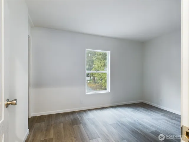 an empty room with wooden floor and window