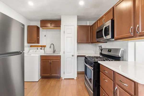 a kitchen with a refrigerator a stove and a dining table with wooden floor