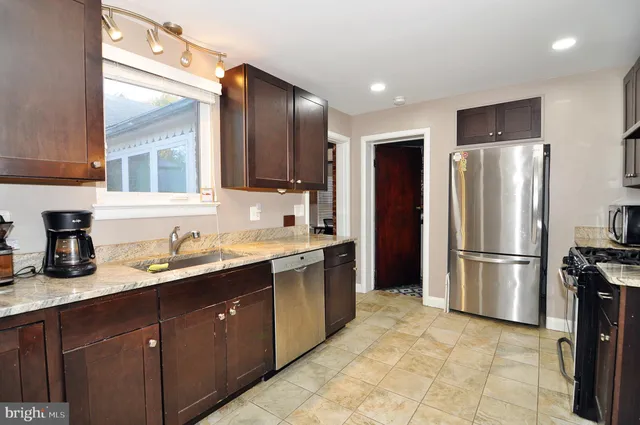 a kitchen with kitchen island granite countertop a sink appliances cabinets and a counter top space