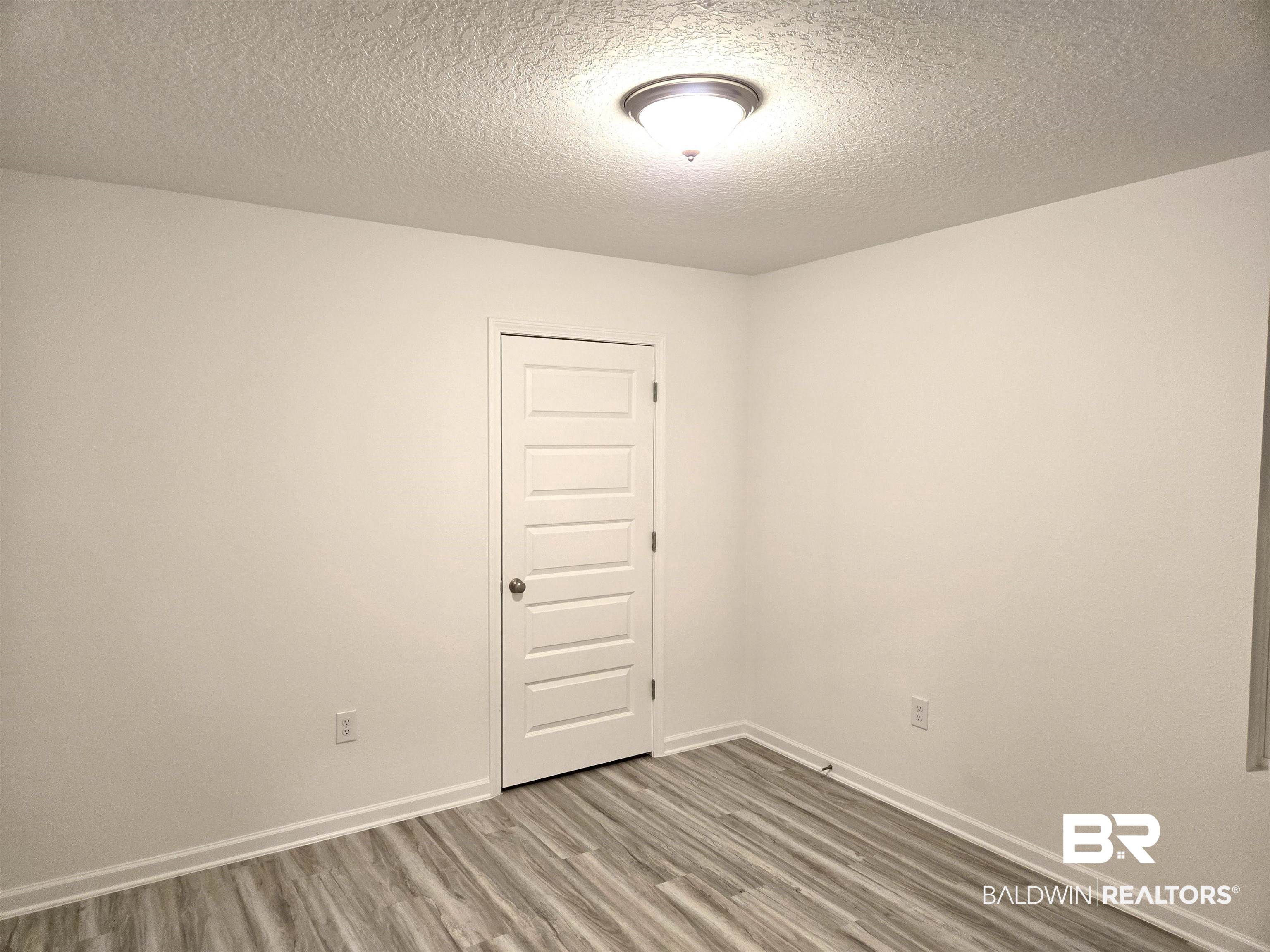 24385 Ringneck Loop Elberta, AL 36530 - Photo 25 of 33 Spare room featuring a textured ceiling and hardwood / wood-style flooring