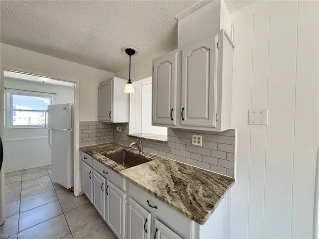 a kitchen with granite countertop a refrigerator and a sink
