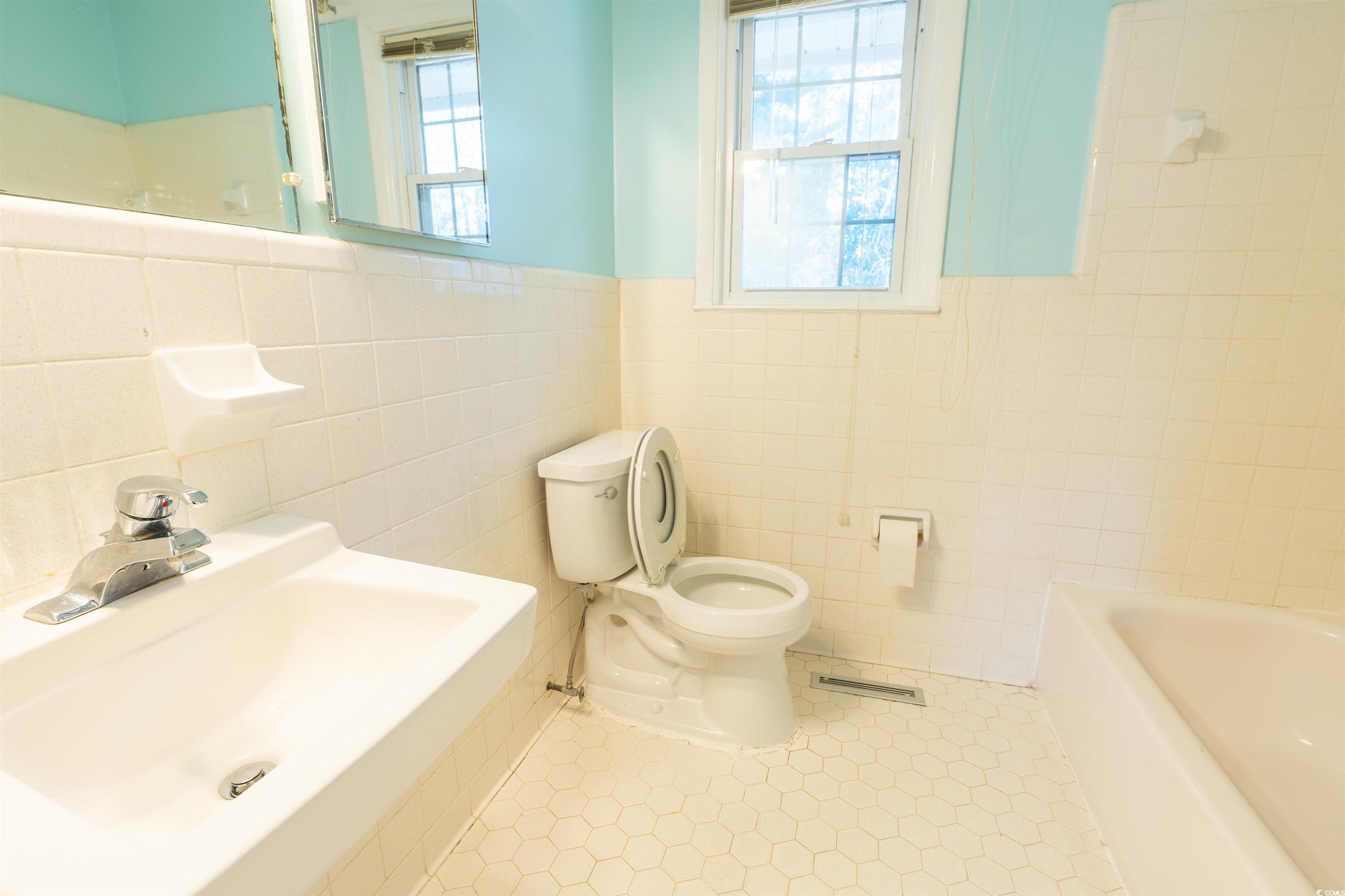 1105 Scott Drive Myrtle Beach, SC 29577 - Photo 8 of 13 Bathroom with a bathing tub, sink, tile walls, toi