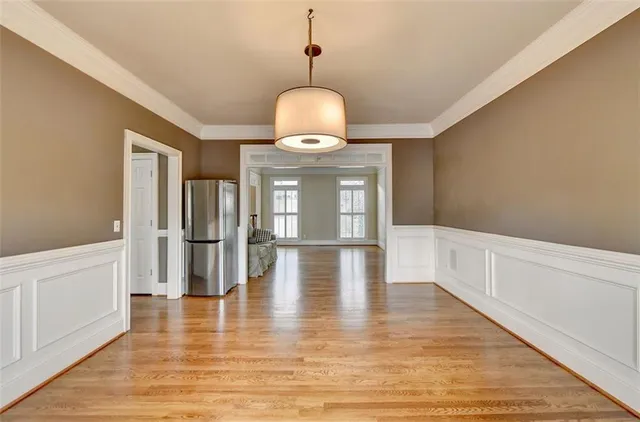 a kitchen with stainless steel appliances granite countertop a stove a sink dishwasher a refrigerator and white cabinets with wooden floor