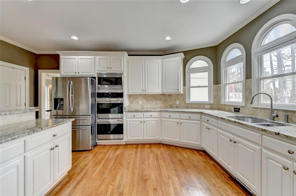7830 Tintern Trace Duluth, GA 30097 - Photo 29 of 91 a kitchen with stainless steel appliances granite countertop a stove a sink dishwasher a refrigerator and white cabinets with wooden floor