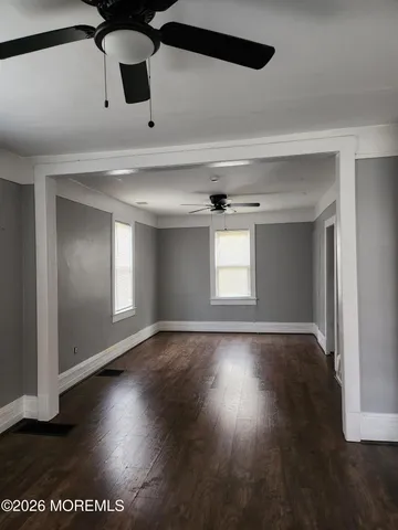 an empty room with wooden floor cabinet and windows